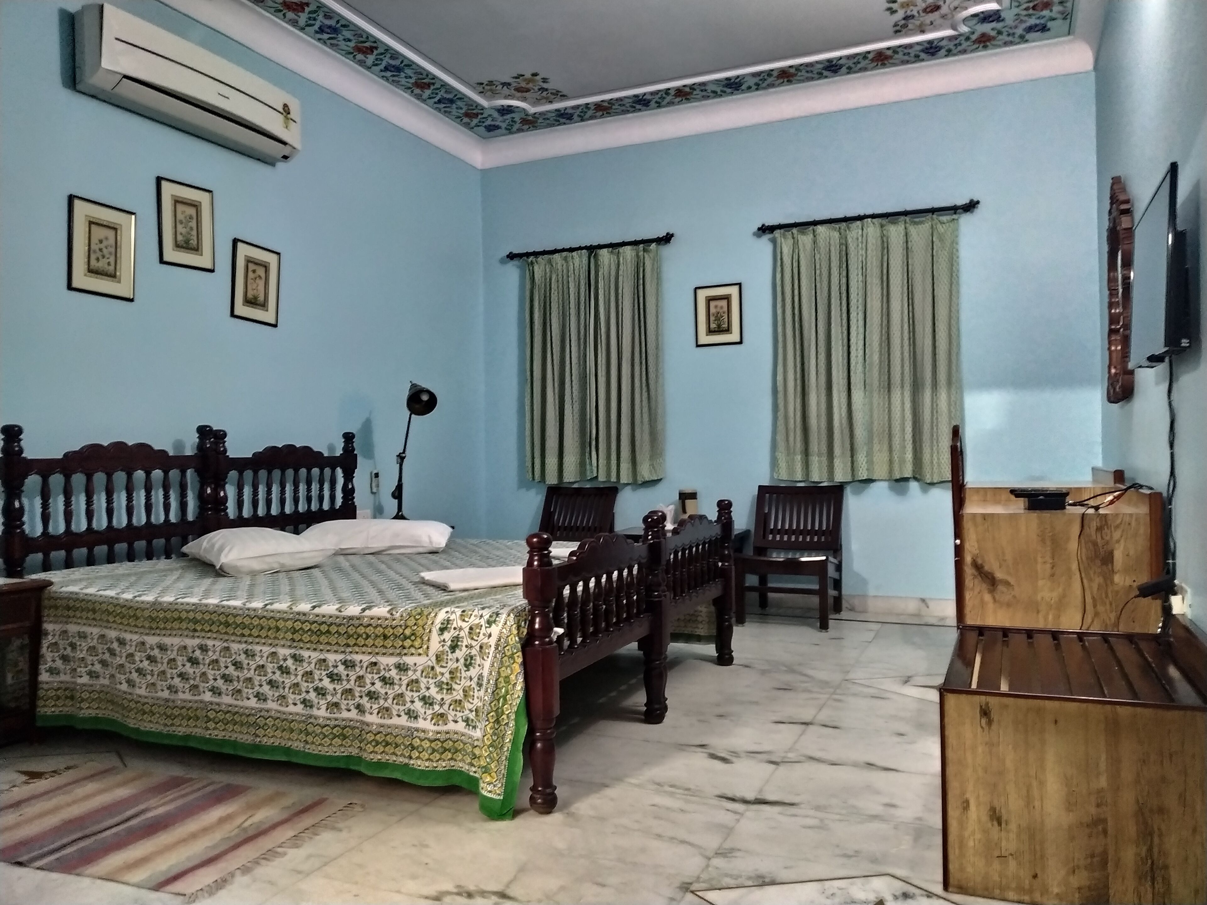 Ein Schlafzimmer mit einem Bett, zwei Stühlen, einem Schreibtisch und einem Fernseher.
