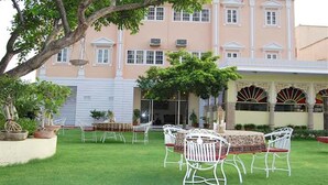 A building with a large lawn, outdoor seating, and a traditional architectural style.