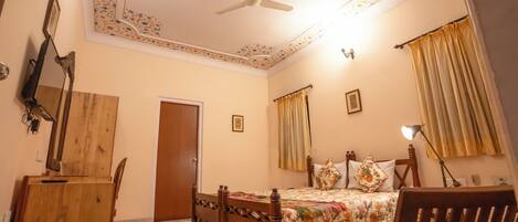 A bedroom with a wooden bed, a ceiling fan, a wooden chair, and a desk.