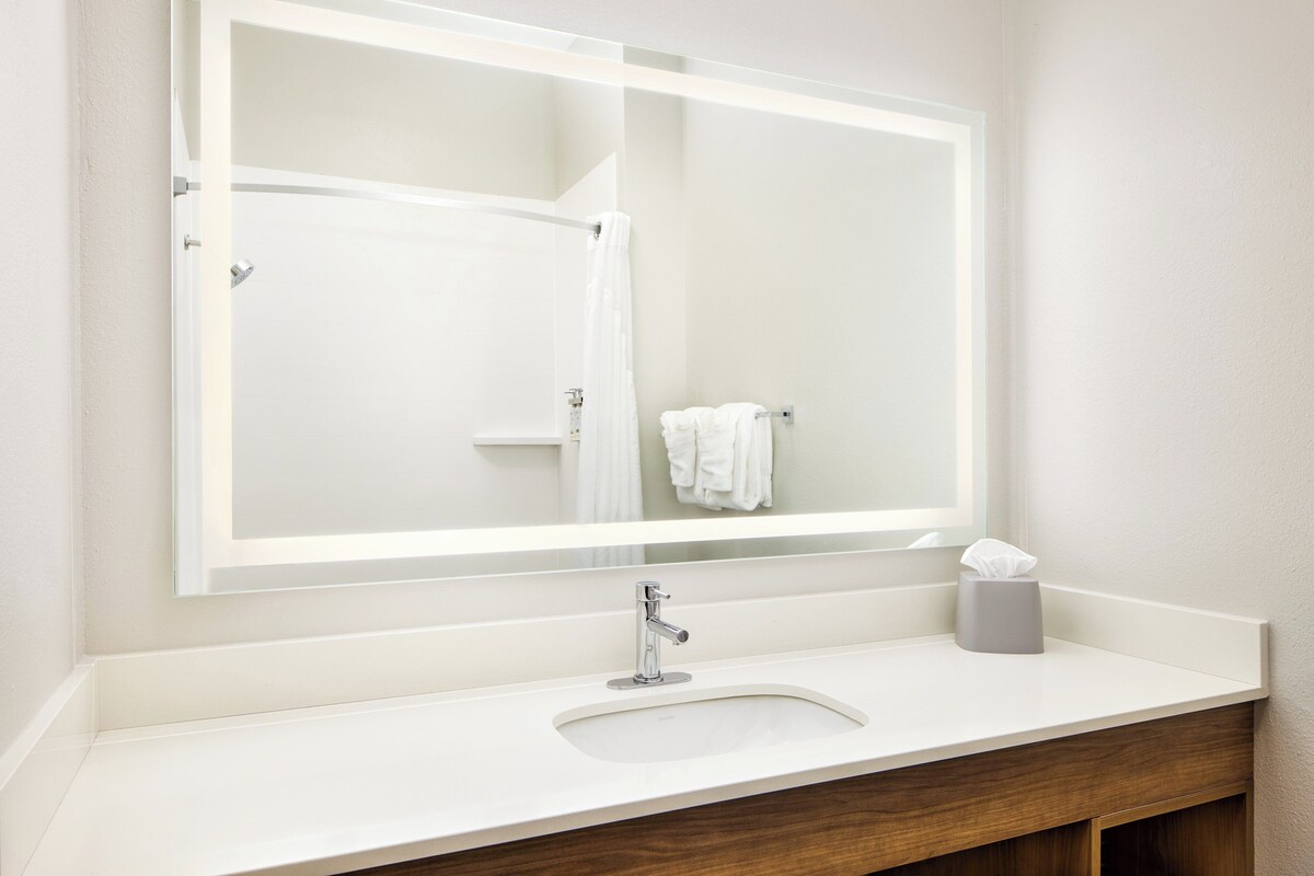 Un baño con un espejo grande, un lavabo y un perchero para toallas.