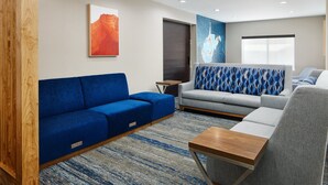 Un salon moderne avec un canapé bleu, un canapé gris et une table basse en bois.