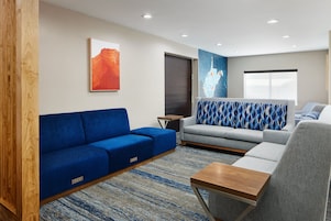Una sala de estar moderna con un sofá azul, un sofá gris y una mesa de centro de madera.