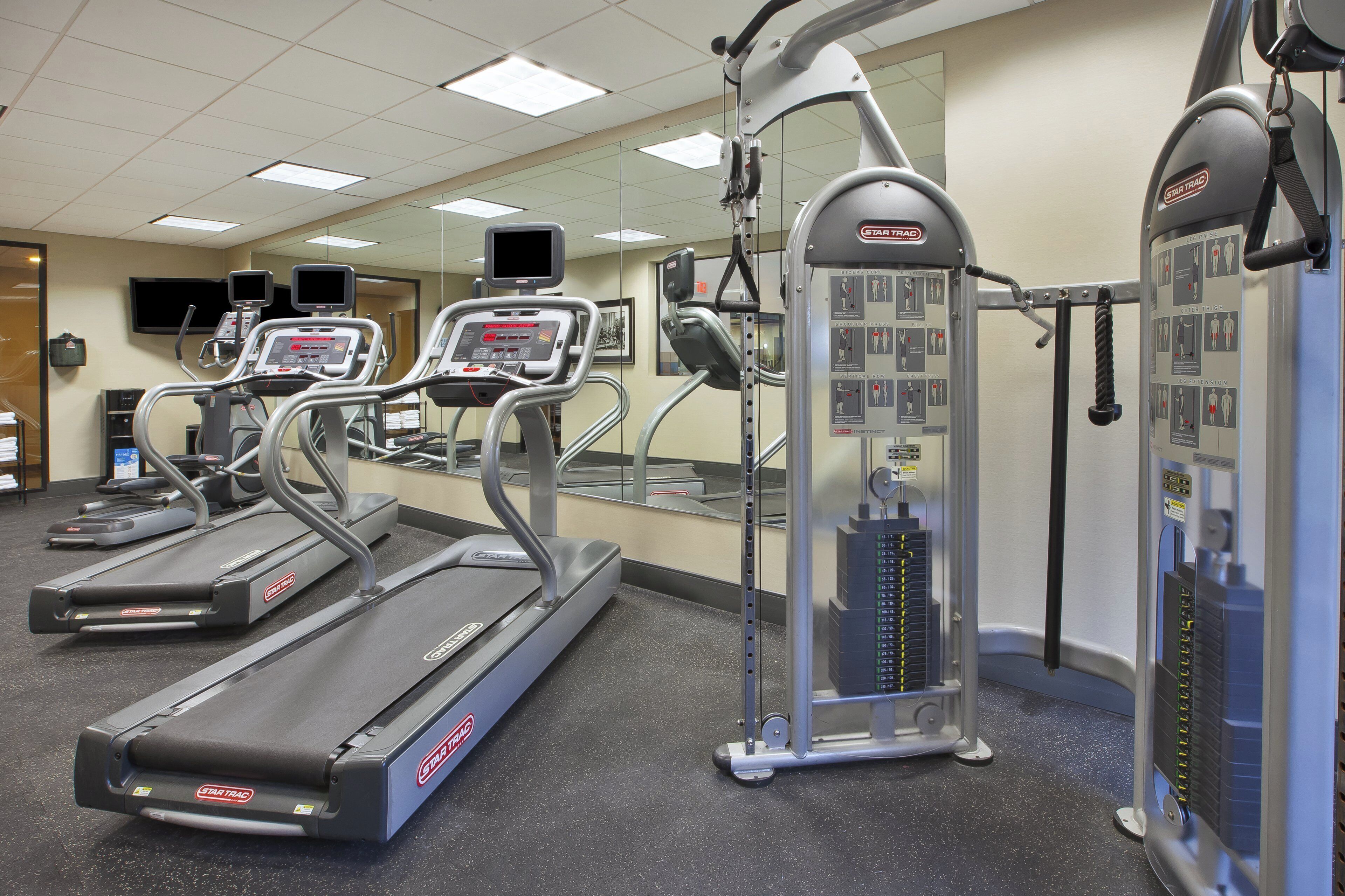 A gym with treadmills, a leg press machine, and a mirrored wall.