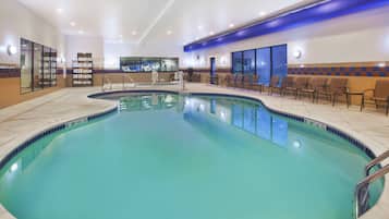 Relax by the oval-shaped pool surrounded by a deck with lounge chairs and a seating area.