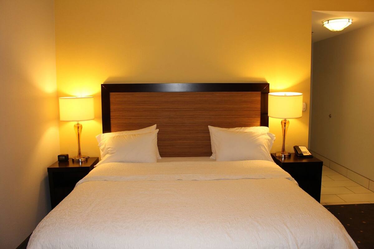 A hotel room with a large bed, two bedside tables with lamps, and a wooden headboard.