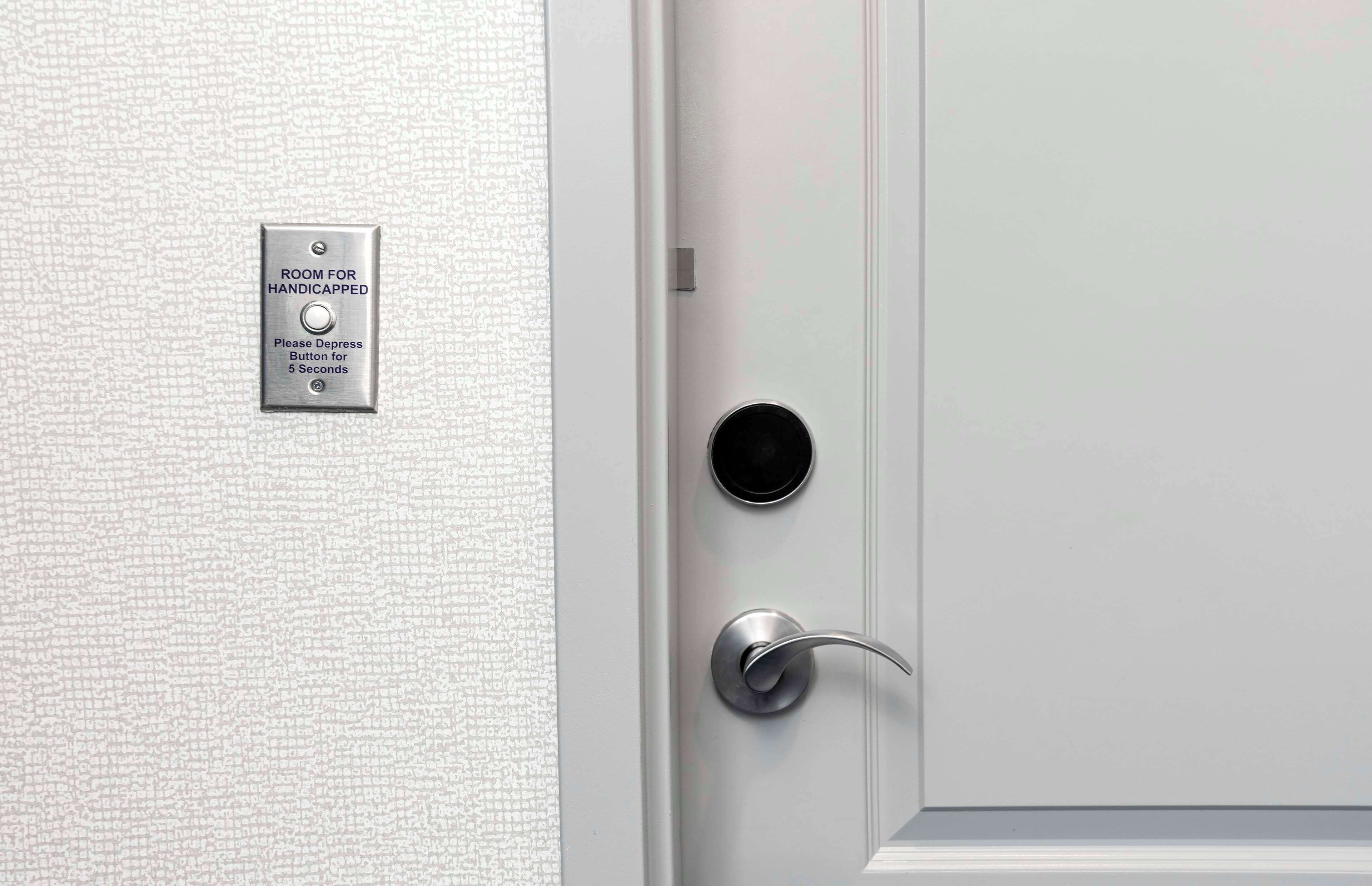 A door with a "ROOM FOR HANDICAPPED" sign and a button for 5 seconds.