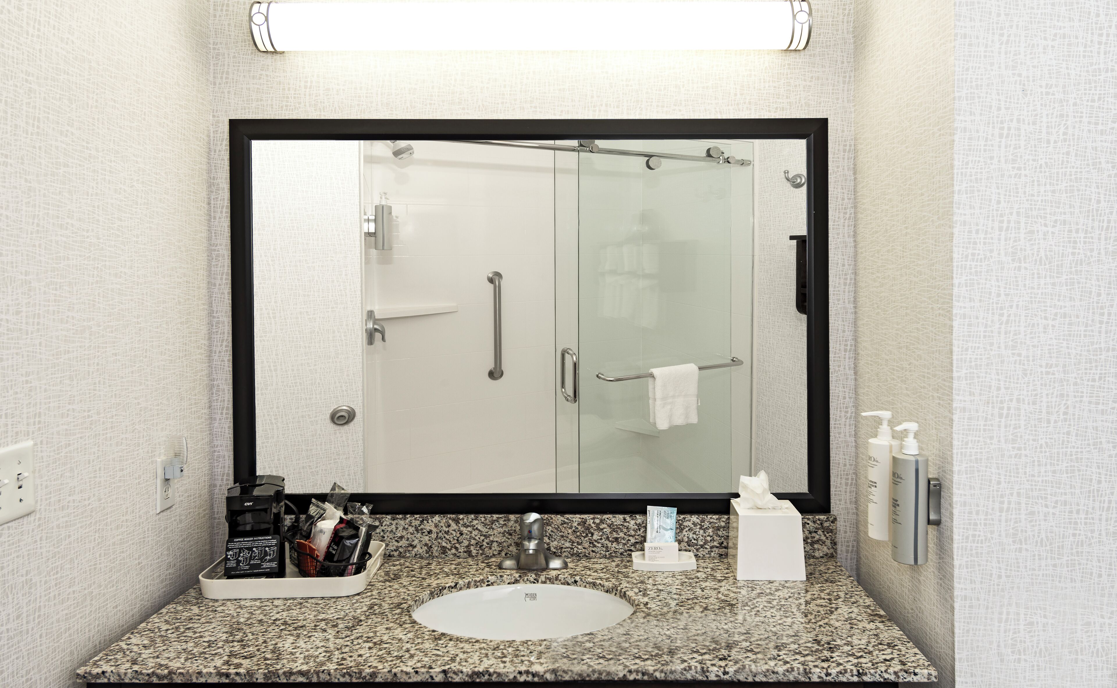 Un baño con un espejo grande, un lavabo y una cabina de ducha de vidrio.