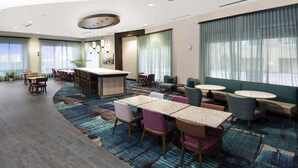 A hotel lobby with a bar, seating area, and a patterned carpet. - Hampton Inn & Suites Raleigh Downtown (Raleigh)