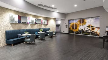 A modern reception area with a stone wall, blue seating, and a large window with a sunflower mural.