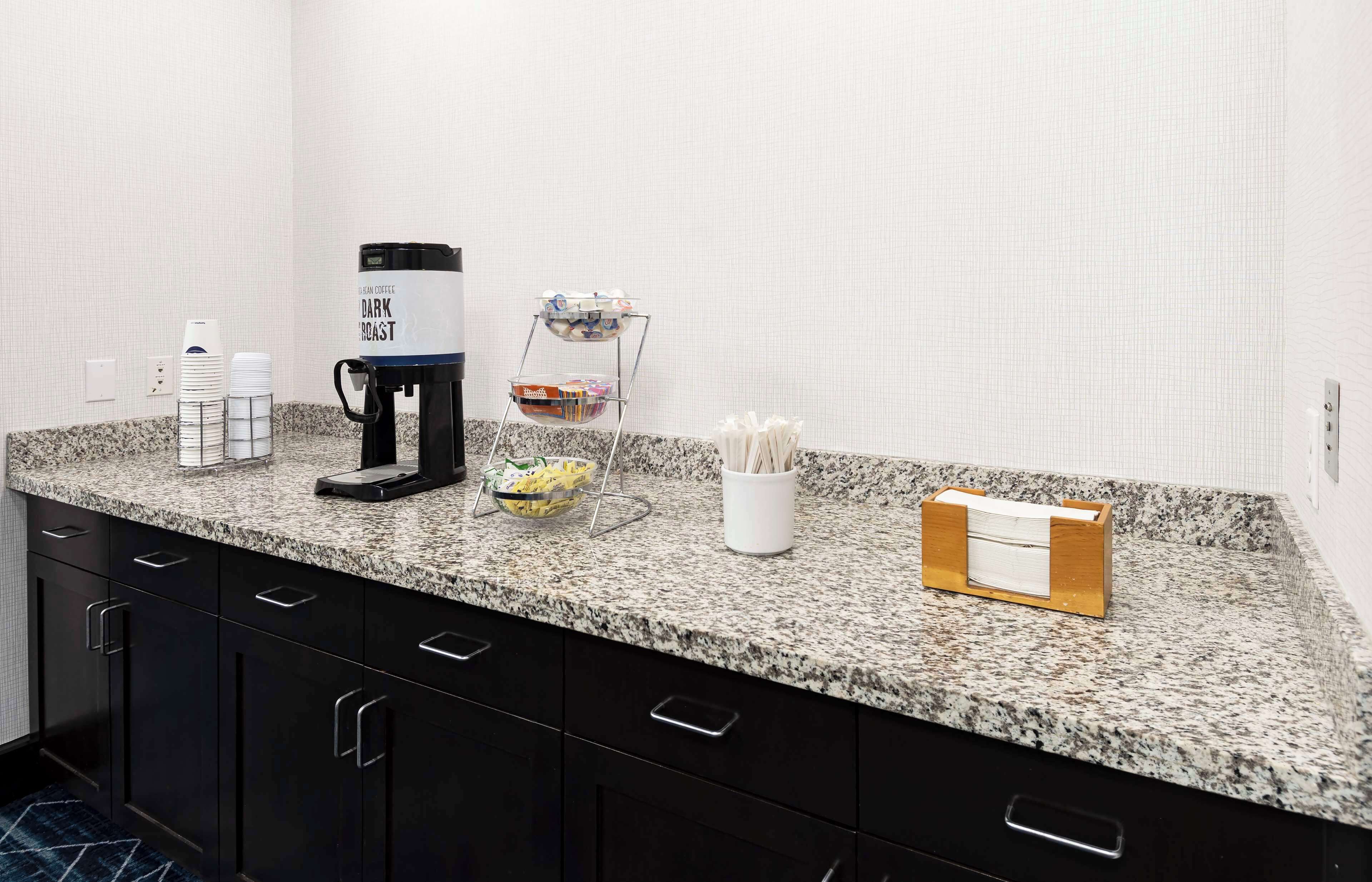 A kitchen counter with a coffee maker, a bowl of fruit, and a napkin holder.