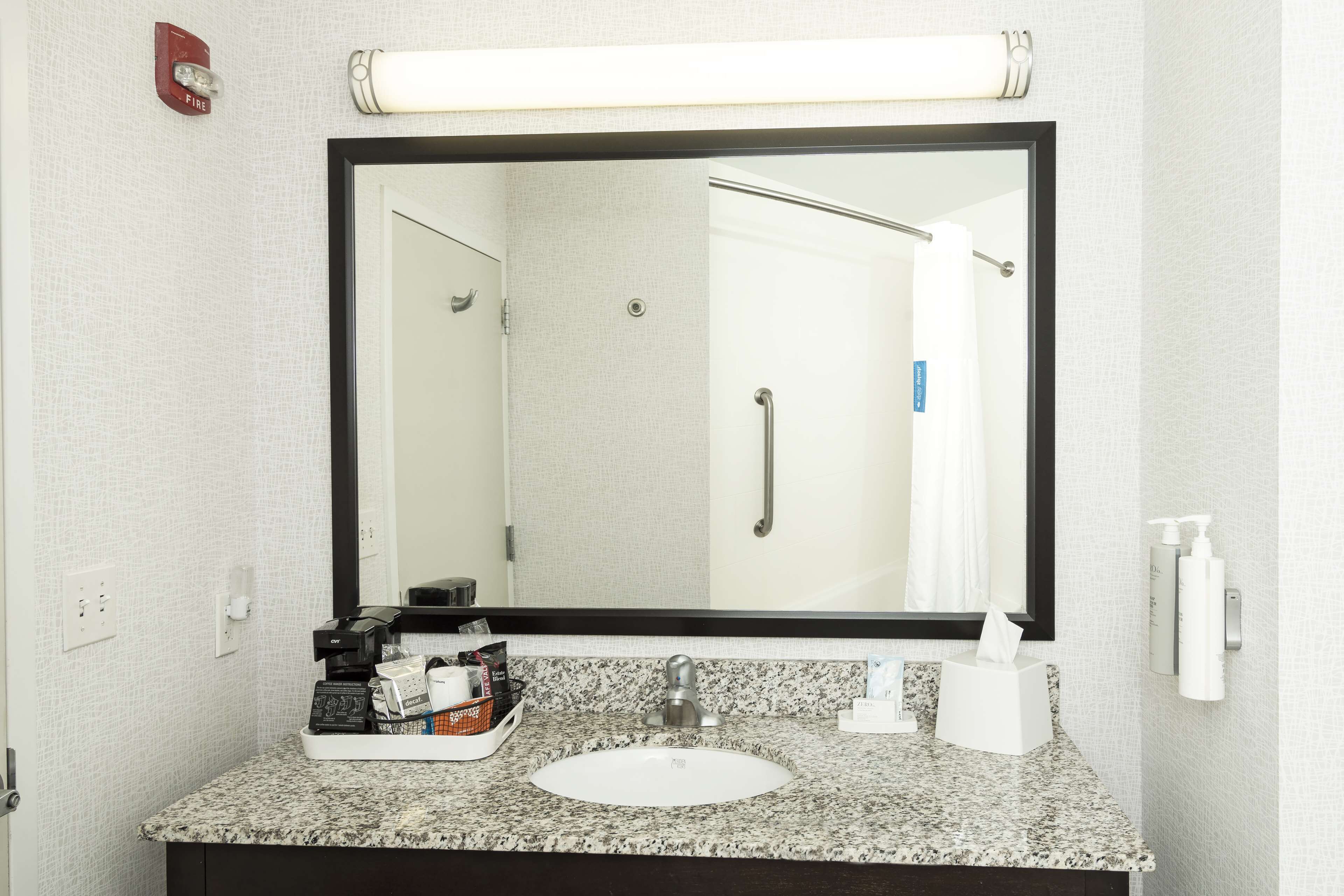 A bathroom with a large mirror, a sink, and toiletries.