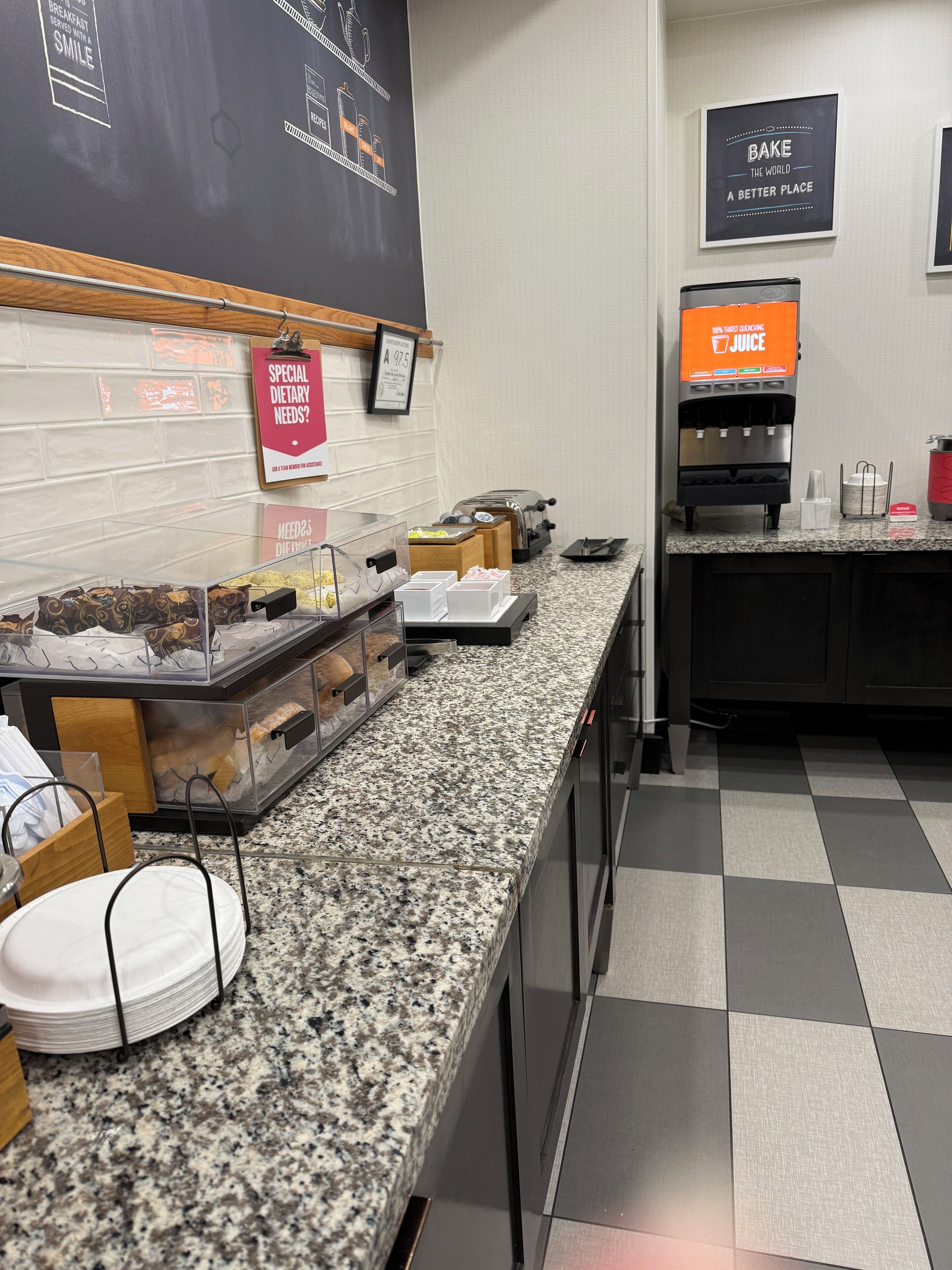 A breakfast bar with various food items and a juice dispenser.