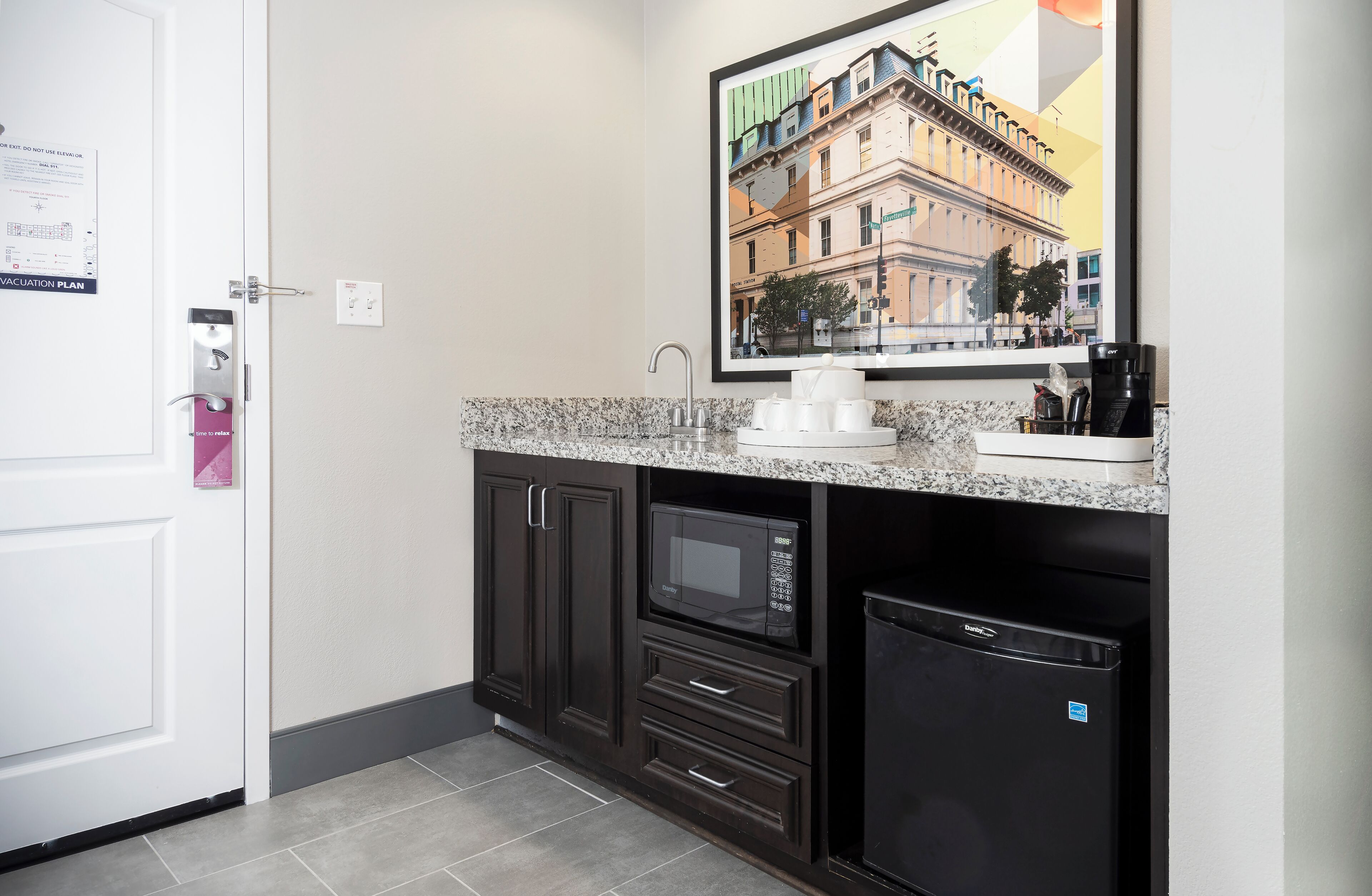 A compact kitchen with dark cabinetry, a built-in microwave, and a coffee maker.
