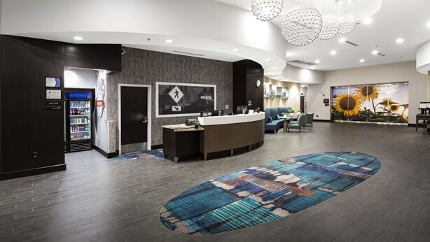 A modern hotel lobby with a reception desk, a seating area, and a large rug. - Hampton Inn & Suites Raleigh Downtown (Raleigh)
