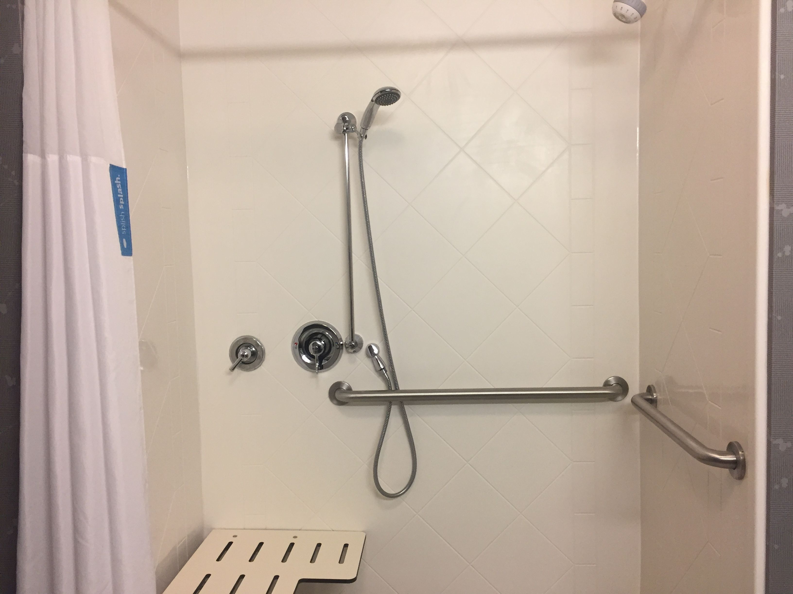 A shower area with a handheld showerhead, a handheld shower attachment, and a grab bar.