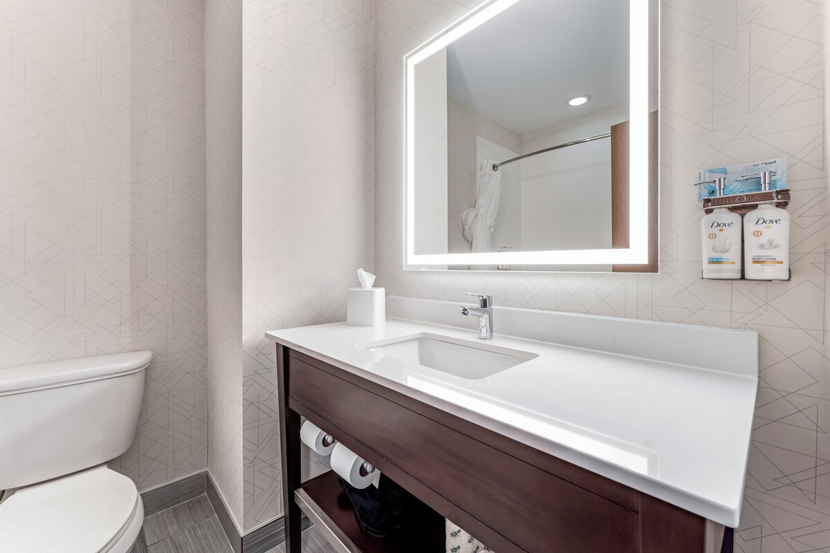 Un baño moderno con un lavabo blanco, un espejo y artículos de aseo en la pared.