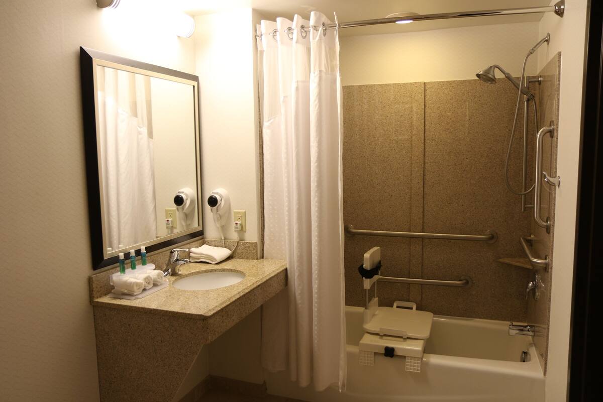 A bathroom with a sink, mirror, and shower.