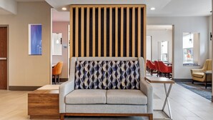 A modern lobby with a sofa, wooden slats, and a patterned cushion.