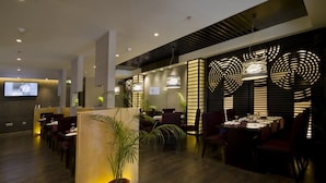 Un interior de restaurante moderno con suelo de madera, mobiliario en tonos oscuros e iluminación ambiental.