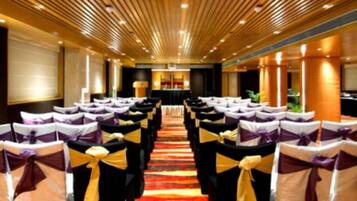 A conference room with rows of chairs, a central aisle, and a carpeted floor.