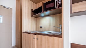 A compact kitchenette with a stainless steel sink, wooden cabinets, and a microwave. - Aparthotel Adagio Lyon Patio Confluence (Lyon)