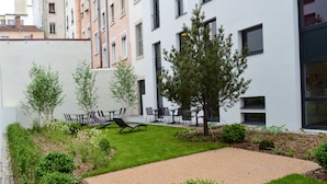 A courtyard with a lawn, seating area, and a gravel path. - Aparthotel Adagio Lyon Patio Confluence (Lyon)