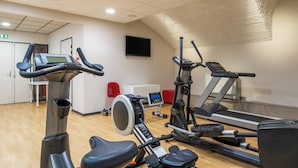 A gym with cardio machines, a TV, and a red chair. - Aparthotel Adagio Lyon Patio Confluence (Lyon)