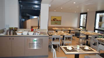Un comedor moderno con mesas dispuestas, servicio de buffet y vistas al exterior.