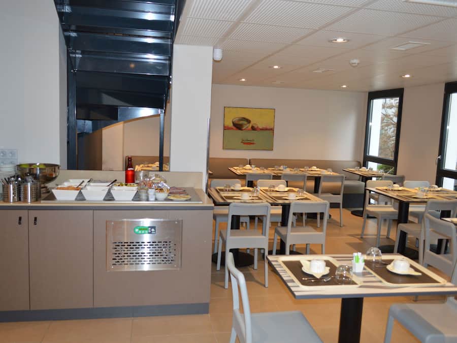 Un comedor moderno con mesas dispuestas, servicio de buffet y vistas al exterior.