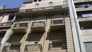 Un edifici de diverses plantes amb balcons, un element decoratiu central i una façana uniforme.