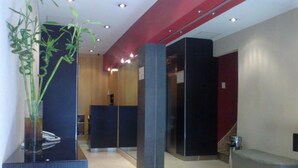 Zona d'entrada moderna amb un panell de vidre, una taulell de recepció i una zona de seients.