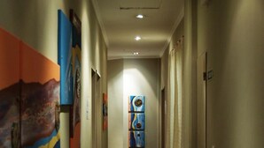 Un passadís amb terra enderrocada, diverses portes a un costat i obra d'art colorida a les parets.