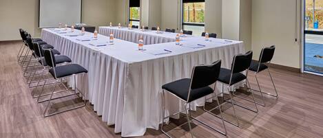 A conference room with a long table, chairs, and a projector screen.