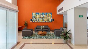 A lobby with a large orange wall, a modern art piece, and a reception desk. - City Express by Marriott San Jose Costa Rica (Ulloa)