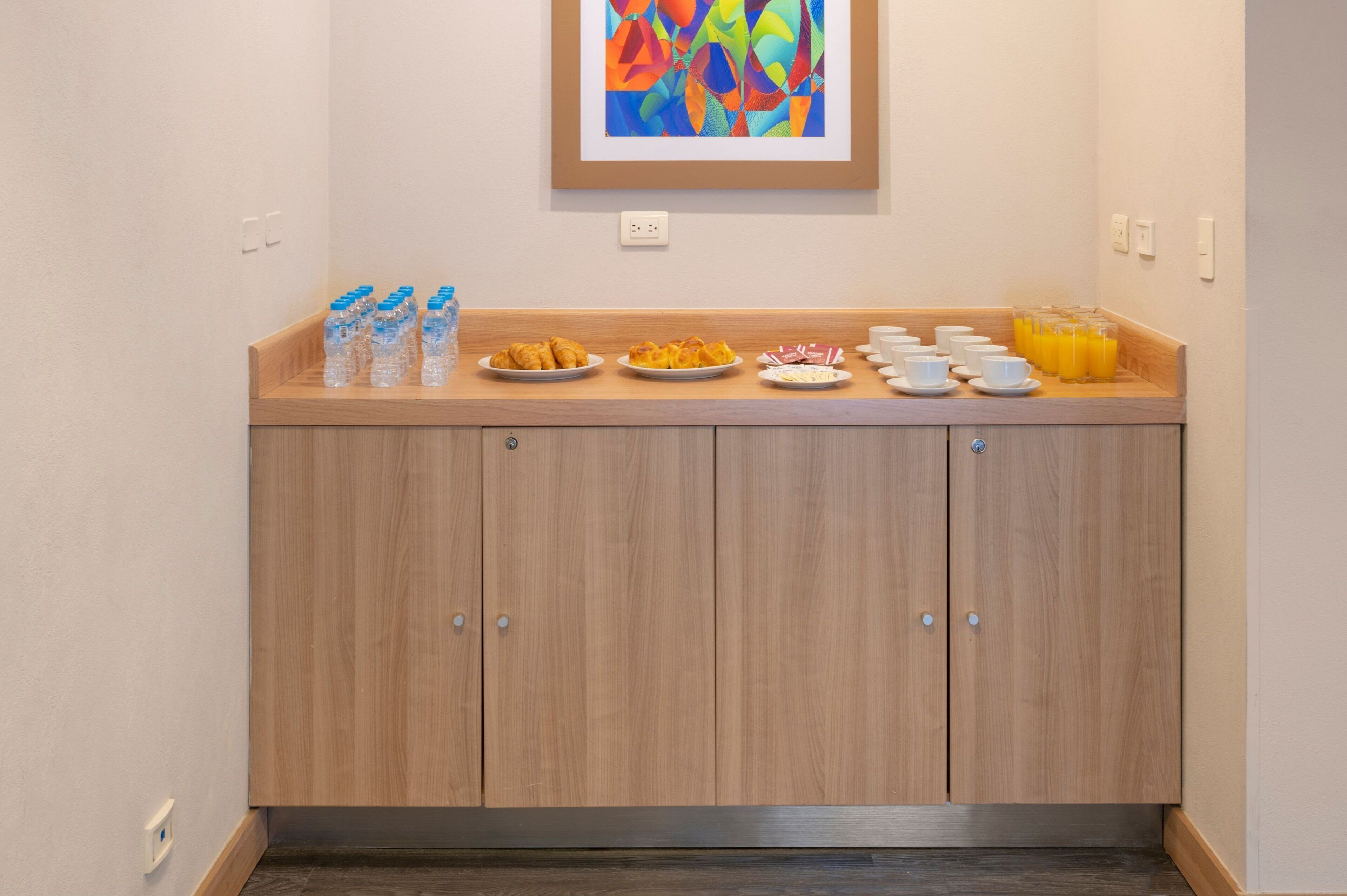 A breakfast bar with water bottles, plates of food, and orange juice.
