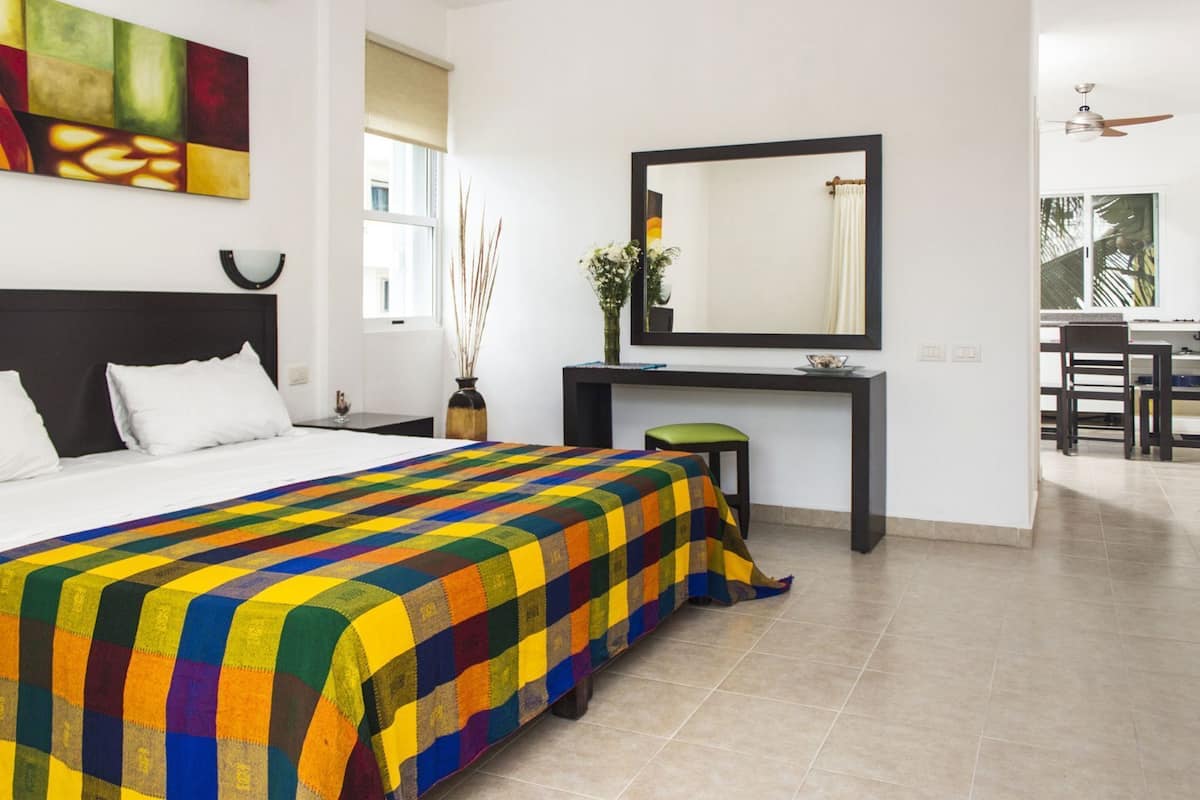 Una habitación de hotel con cama, escritorio, silla, espejo y ventana.