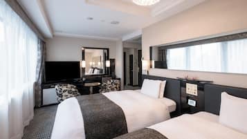 A hotel room with two beds, a desk with a TV, a mirror, and a window with curtains.