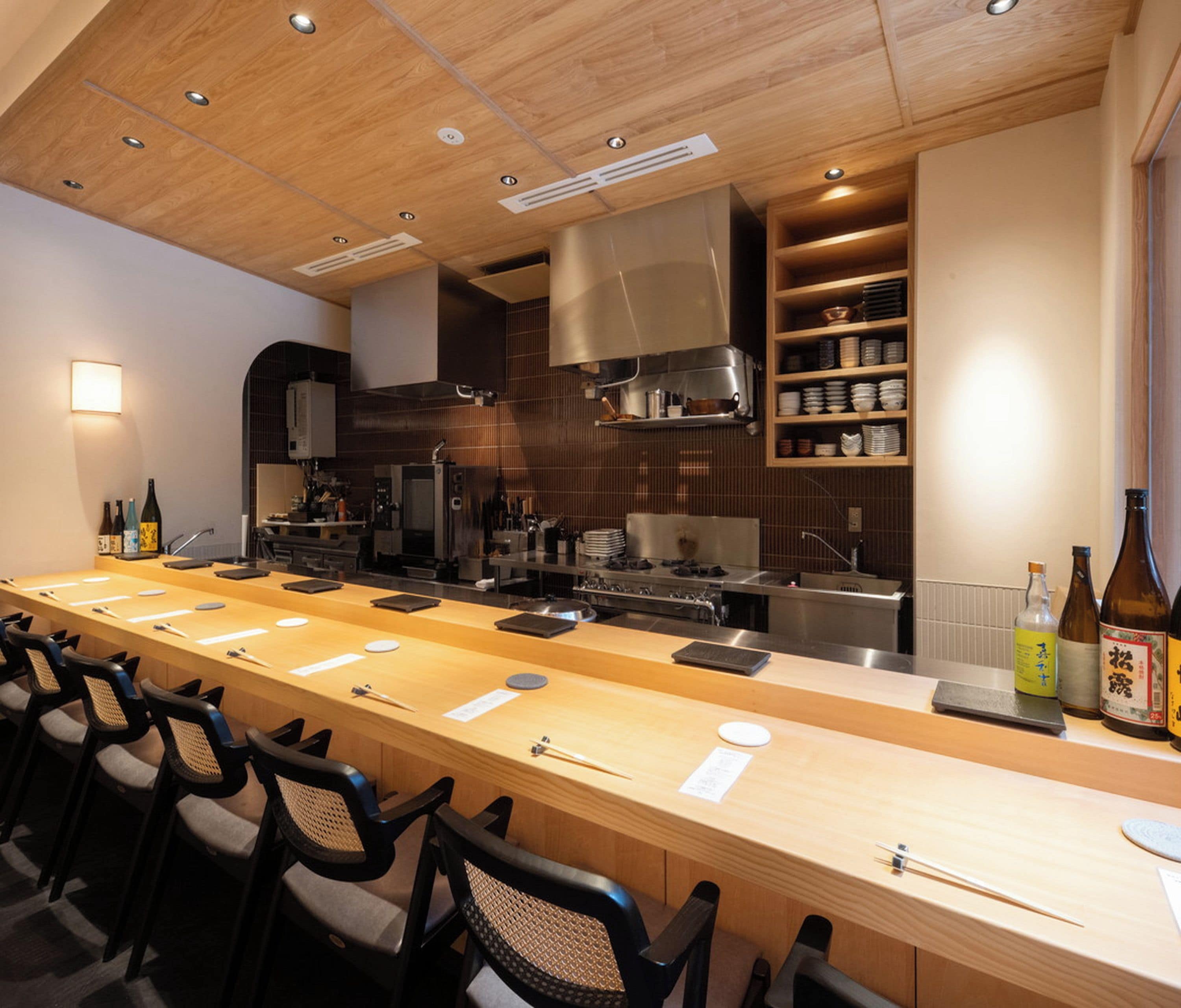 A modern kitchen with a long counter, bar stools, and a variety of cooking appliances.