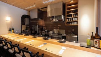 A modern kitchen with a long counter, bar stools, and a variety of cooking appliances.