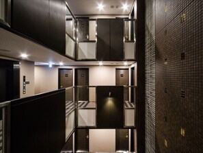 Un área de ascensor moderna con varias puertas, un panel de control y una partición de vidrio.