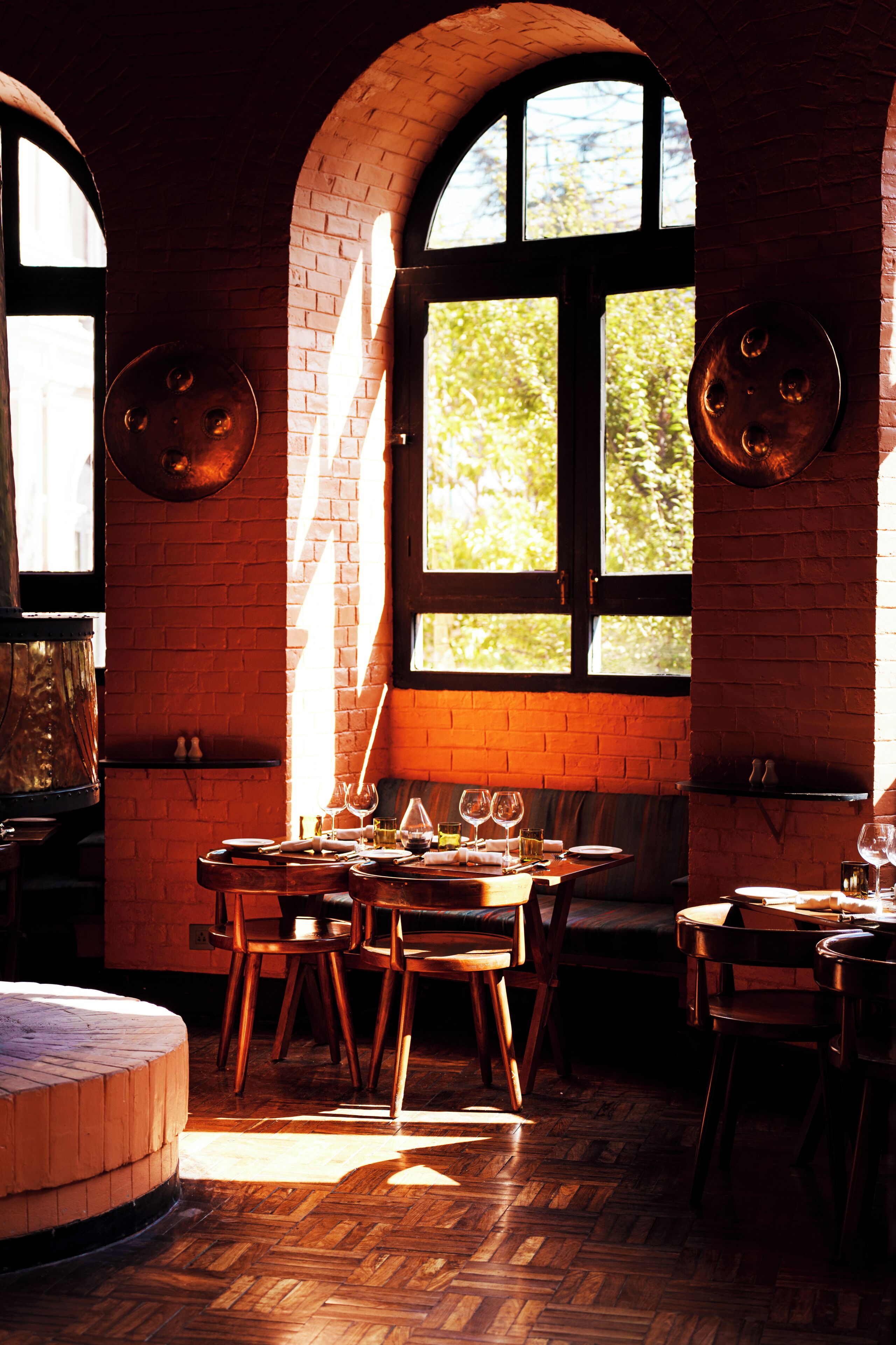 A restaurant with brick walls, wooden furniture, and large windows allowing natural light.