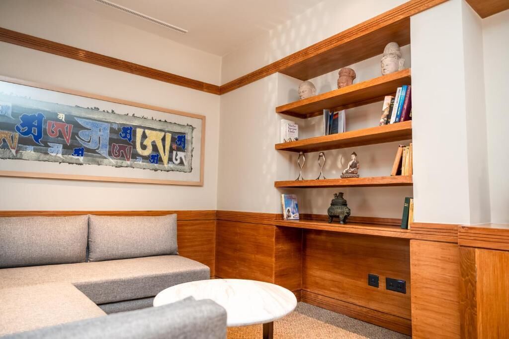 A cozy corner with a grey sofa, a small round table, and a wooden bookshelf with decorative items and books.