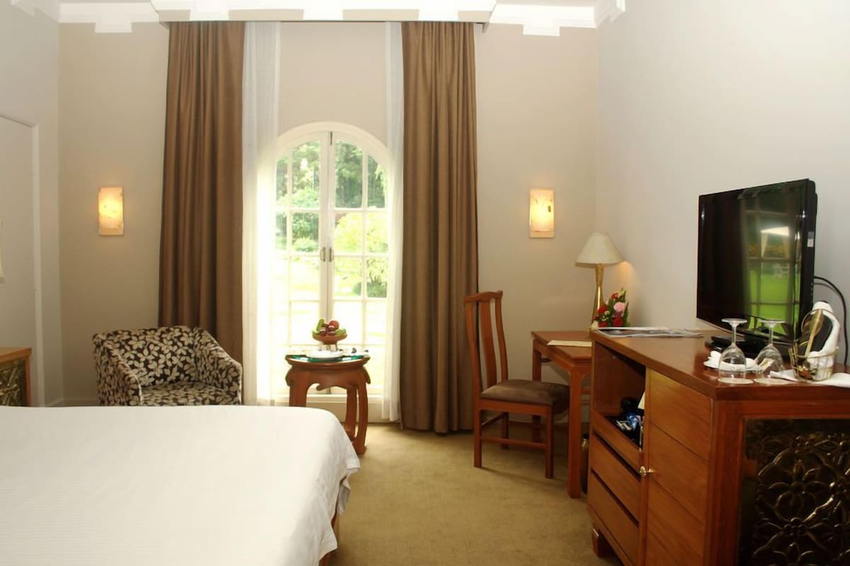 A hotel room with a bed, a desk, a chair, a television, and a window with curtains.