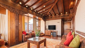 Un interior tradicional con techo de madera, un conjunto de sofás, un televisor y un mueble decorativo.