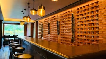 A bar area with a brick wall, hanging lights, and bar stools.