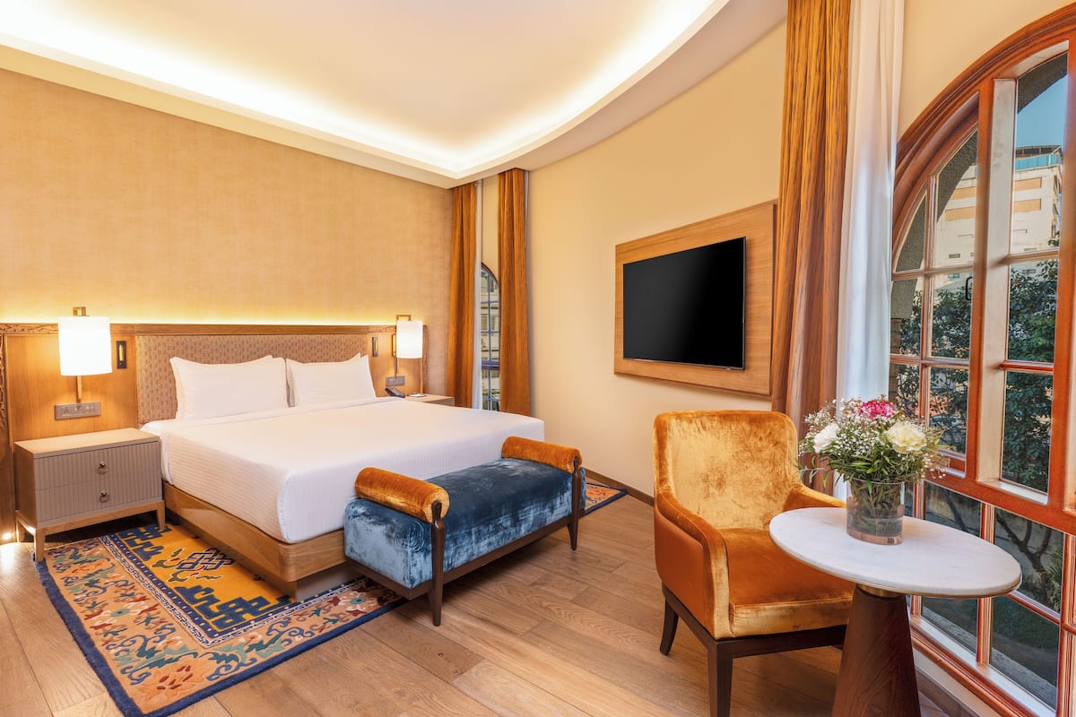 Ein Hotelzimmer mit Bett, Nachttisch, Stuhl, Fernseher und einem Fenster mit Blick.