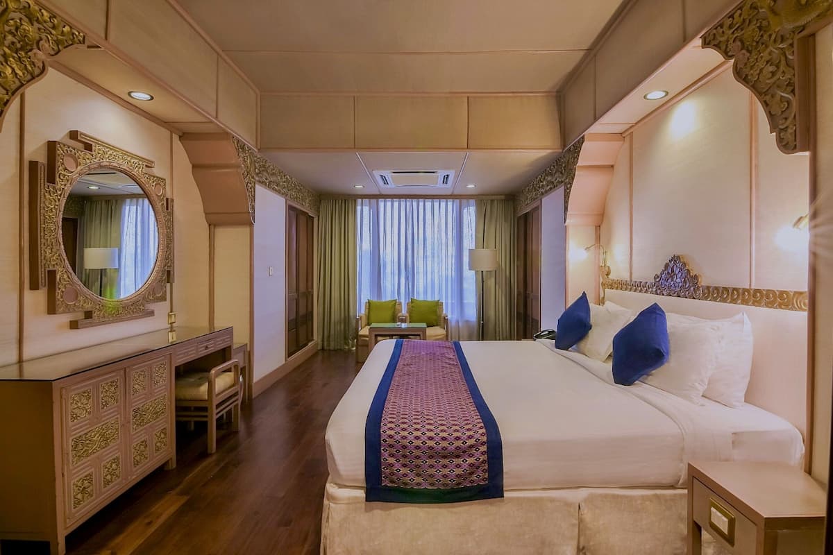Ein Hotelzimmer mit einem großen Bett, einem Schminktisch, einem Spiegel, einem Schreibtisch und einem Stuhl.
