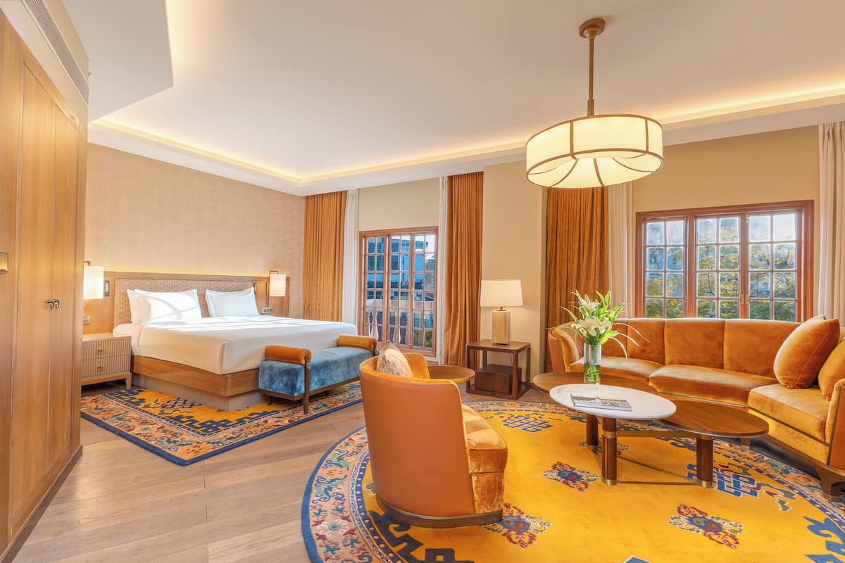 Ein Hotelzimmer mit Bett, Sofa, Sessel, Couchtisch und Blick ins Freie.