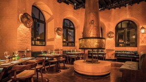 Un restaurante con paredes de ladrillo, ventanas de arco y mobiliario de madera.