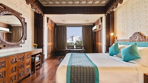 Habitación de hotel con una cama grande, un escritorio, una silla, un espejo y vistas a edificios.